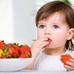 a little girl eating strawberries