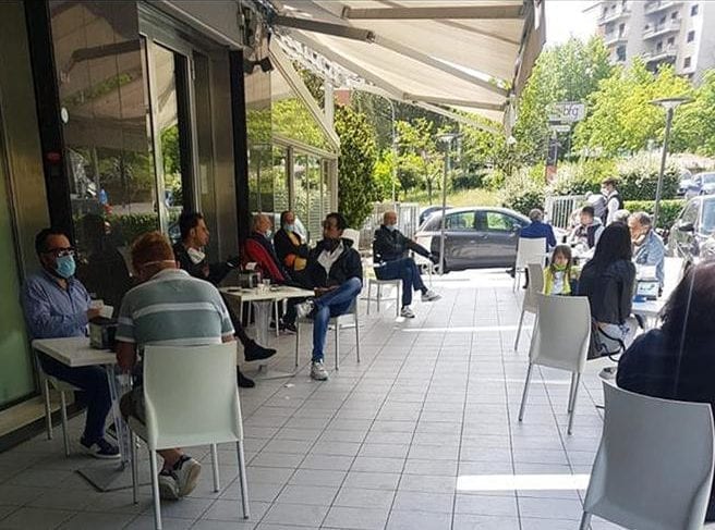 Clienti seduti ai tavoli di un bar consumano il loro caffè all aperto