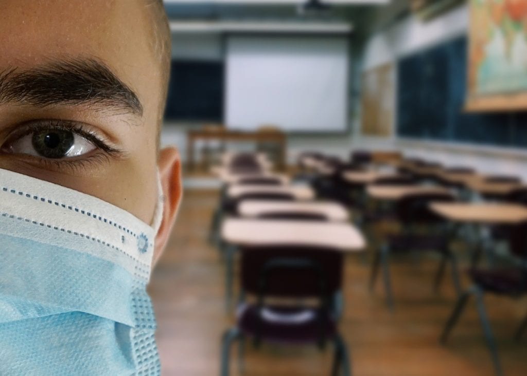 Riapertura scuole, uno studente in classe indossa la mascherina