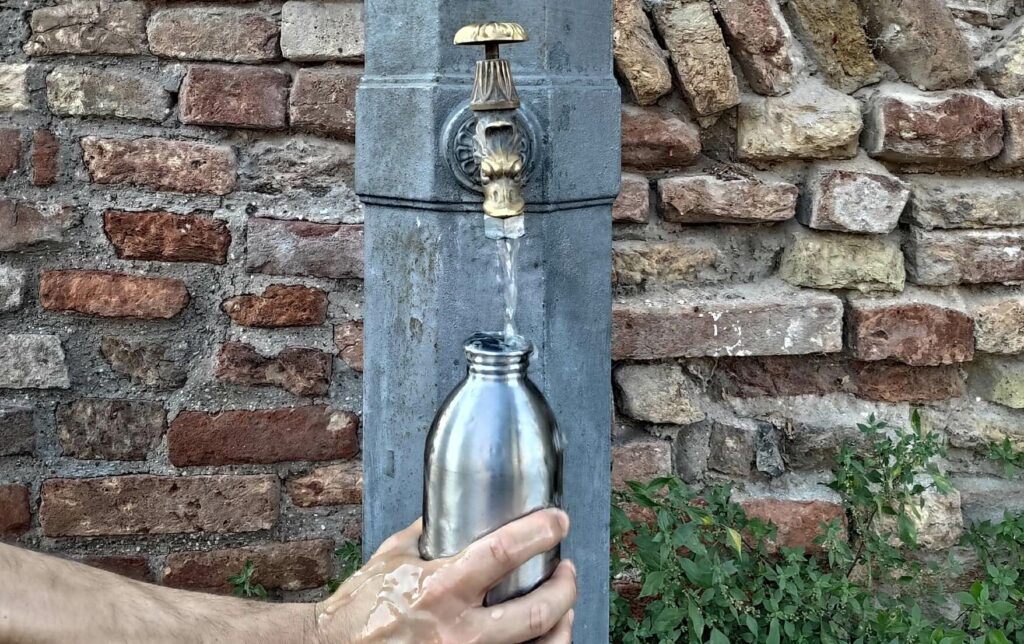 Acqua pubblica: persona che riempie la borraccia presso una fontana