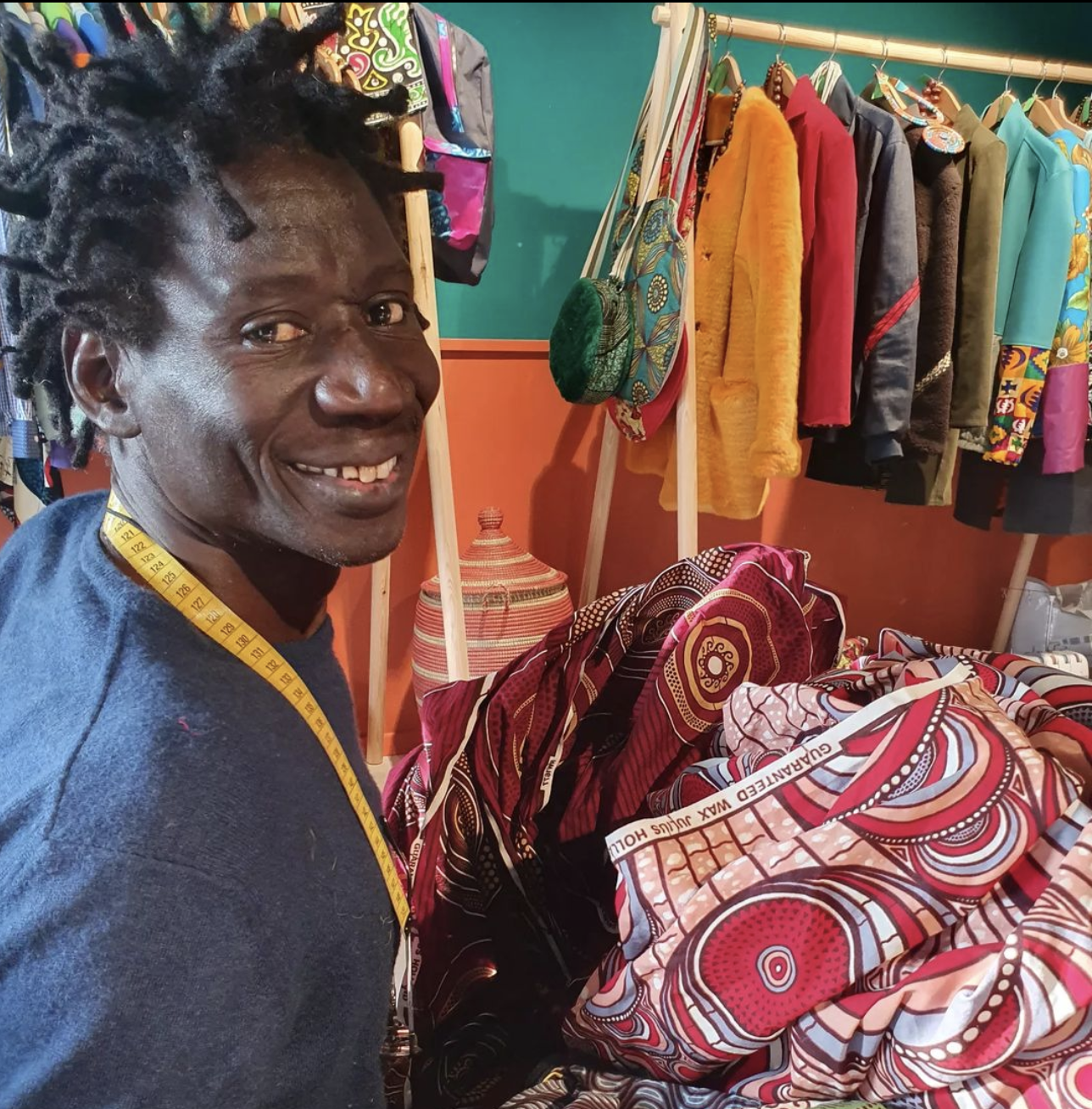 Cheikh Diattara sarto senegalese sorride mentre lavora nella sua sartoria