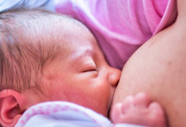 Una neonata viene allattata al seno materno