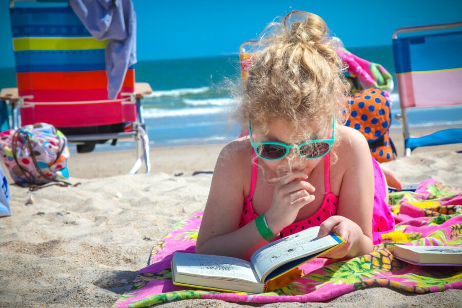 compiti delle vacanze bambina in spiaggia con libro