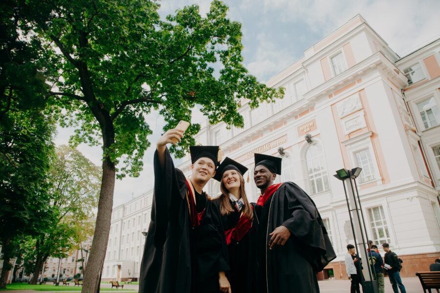 L'attrattività delle università italiane tra eccellenza accademica e politiche di accesso nel 2023. Gli studenti tra opportunità e occupabilità. 3 donne in abito accademico nero in piedi vicino all'albero verde durante il giorno.