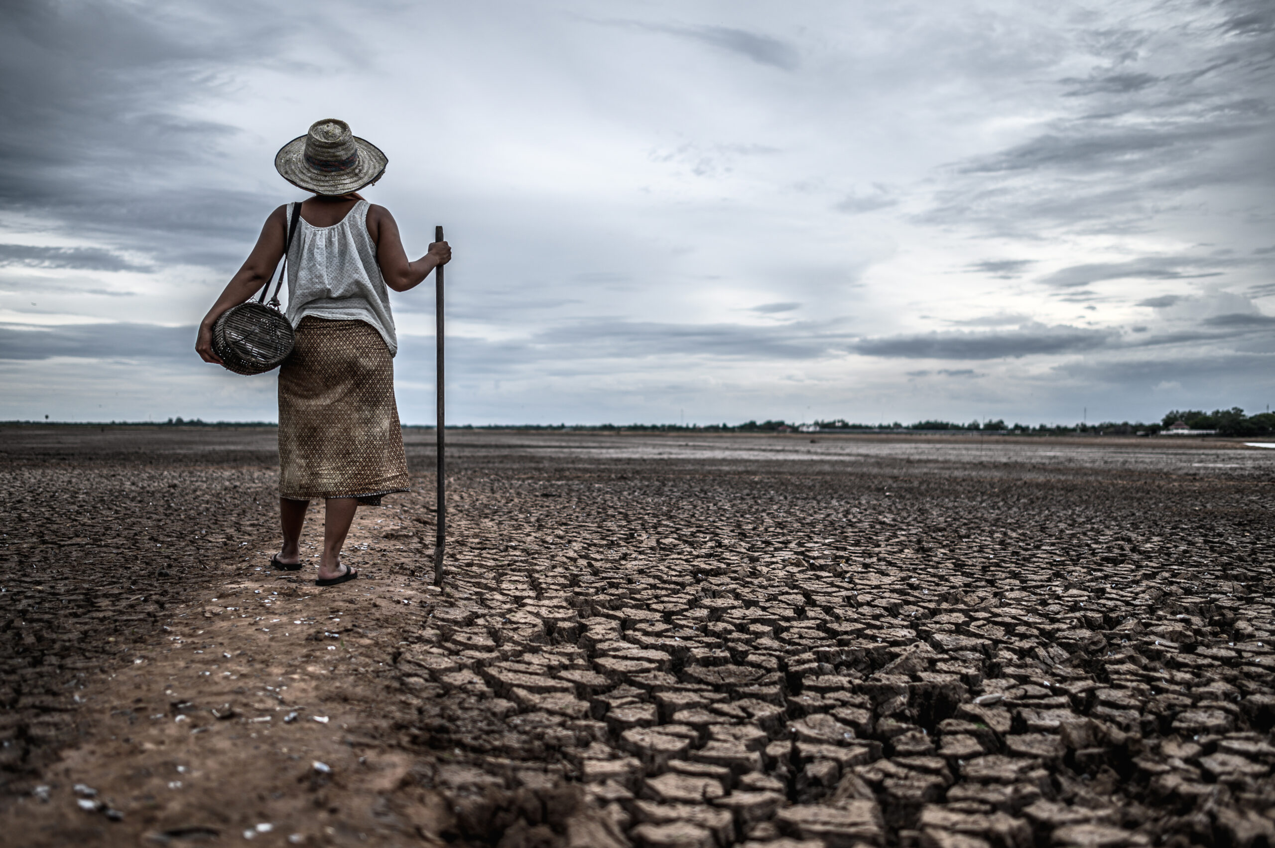 Crisi idrica: donna cammina su un terreno arido