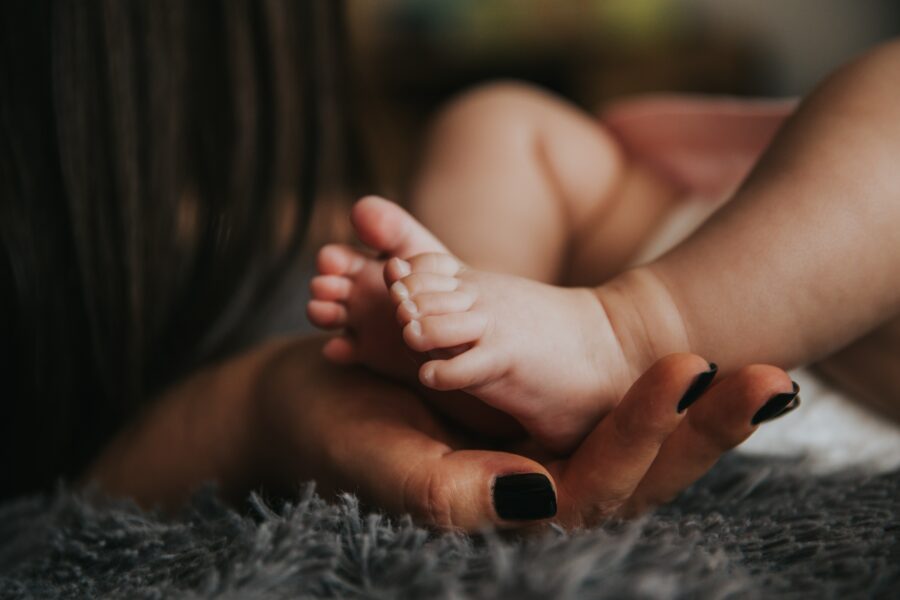 Essere madre oggi: dal baby blues alla teoria del "good enough". Mamma che tocca i piedini del suo bambino.