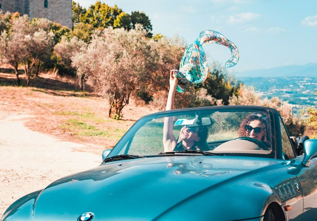Sicurezza stradale jpg: due ragazze viaggiano sorridenti su un'auto decappottabile.