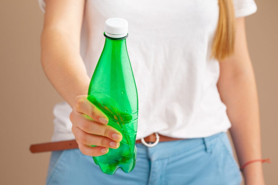 Inquinamento plastica. Una ragazza che ha in mano una bottiglia vuota di plastica