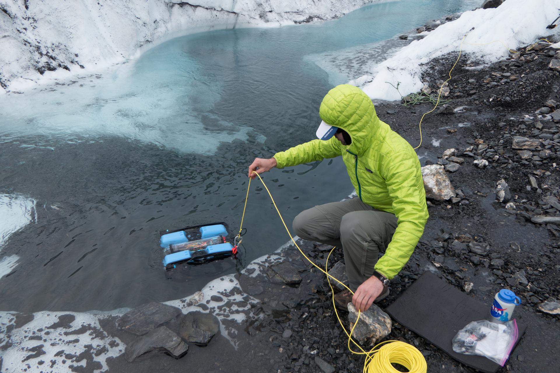 Ghiacciai alpini: ricercatore che effettua dei campionamenti nell'acqua di un ghiacciaio