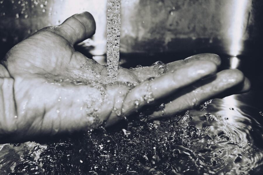 crisi idrica e cambiamenti climatici: mano a contatto con acqua del rubinetto.