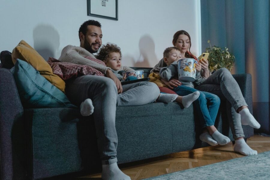 genitori e figli sul divano vedono insieme la tv, seguendo i programmi dei nuovi palinsesti Rai