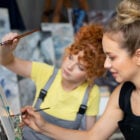 Due artiste all’opera nel proprio studio, a rappresentare il potenziale che può emergere quando il reddito di cittadinanza non è solo un aiuto, ma un investimento mirato nella cultura.