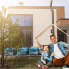 energia sostenibile: uomo e bambina davanti una casa moderna